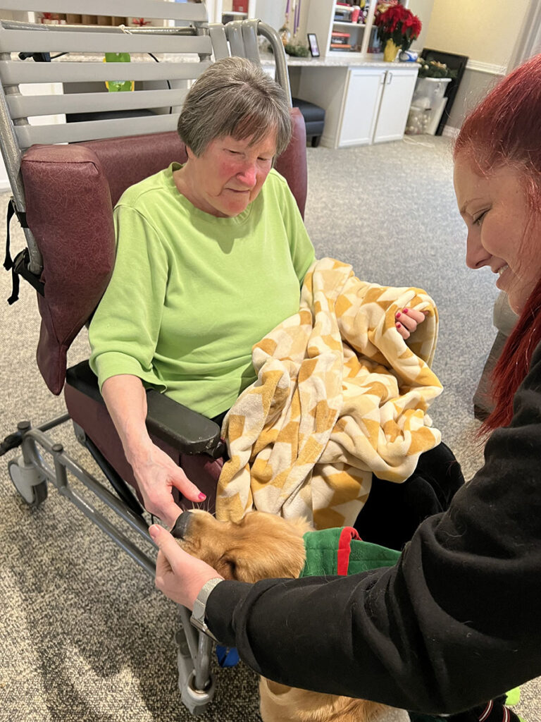 A caring volunteer brings a therapy dog to bring joy and comfort to memory care residents.