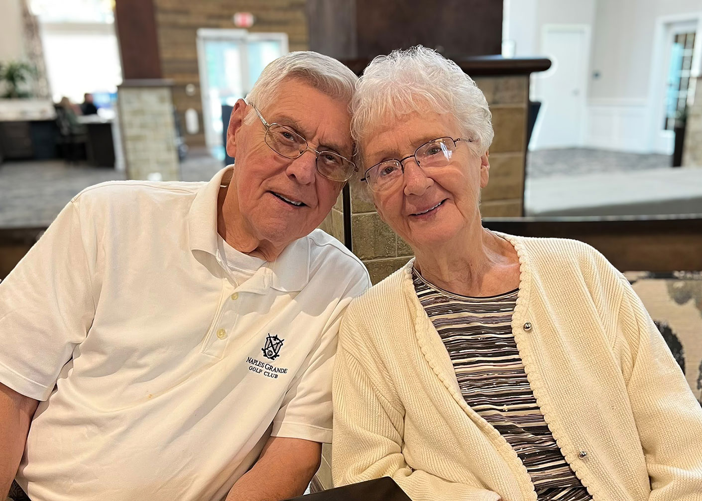 A senior man and woman smile with their heads resting together.