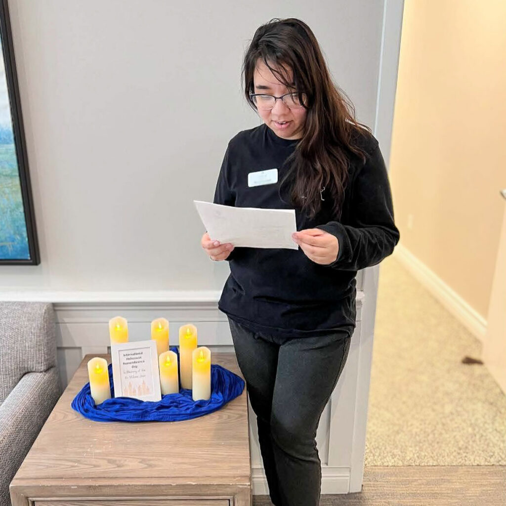 A team member reads from an informational material alongside candles glowing for Holocaust Remembrance Day.