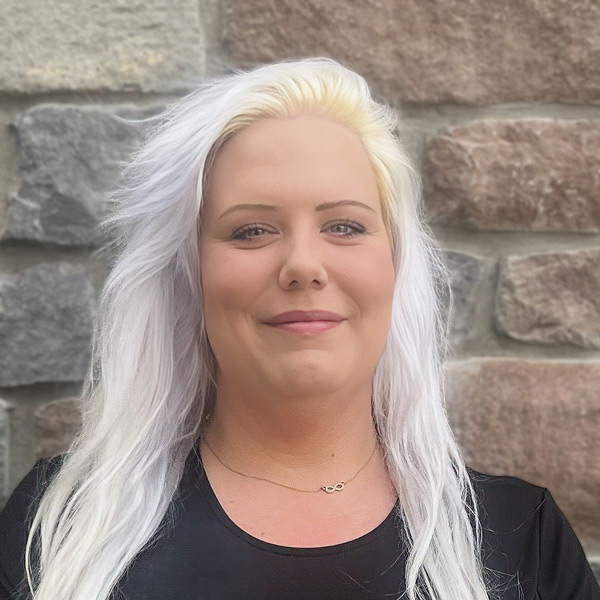 Brittany Duvall, Memory Care Director at Vitalia Westlake, smiling in a professional headshot, wearing a black top, with a stone wall background.